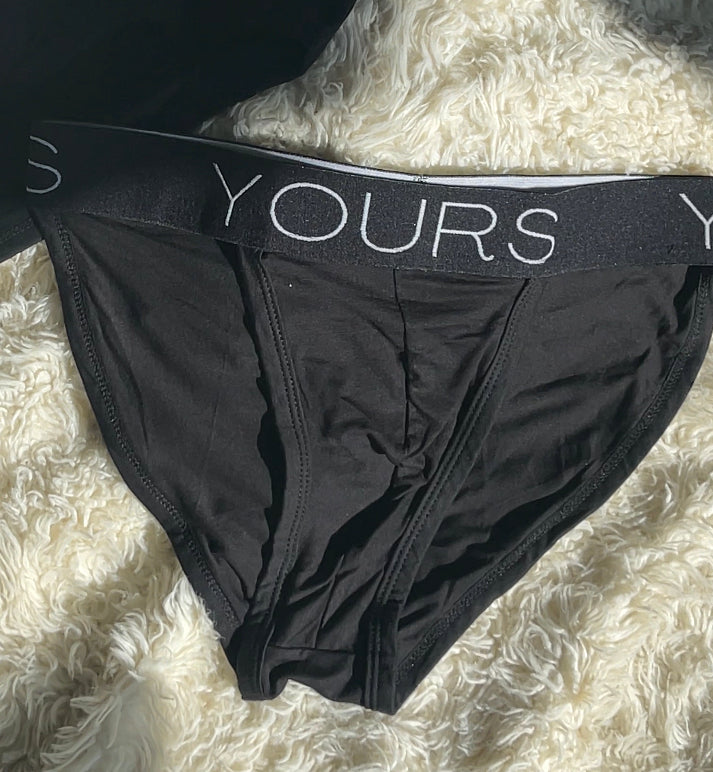 Black tanga underwear on white carpet