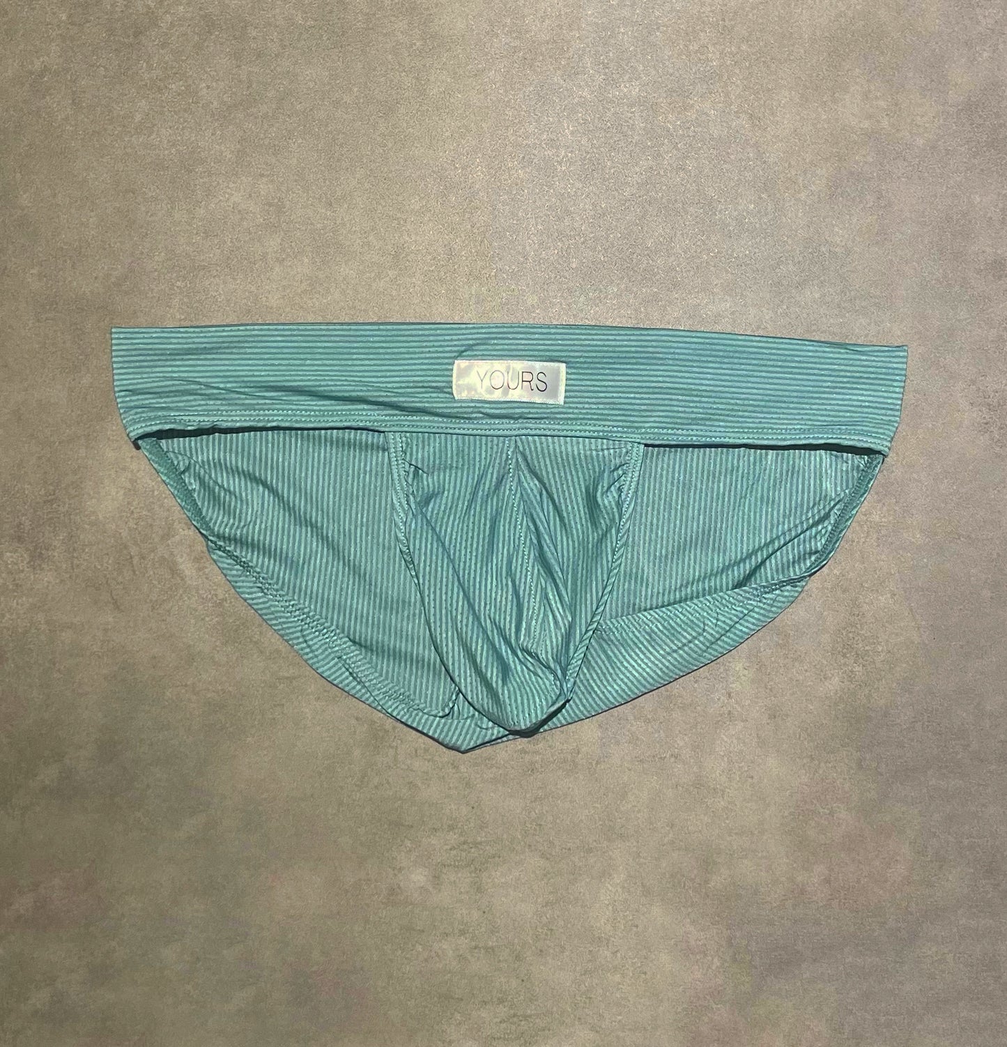 Flat lay photo of turquoise colored striped briefs