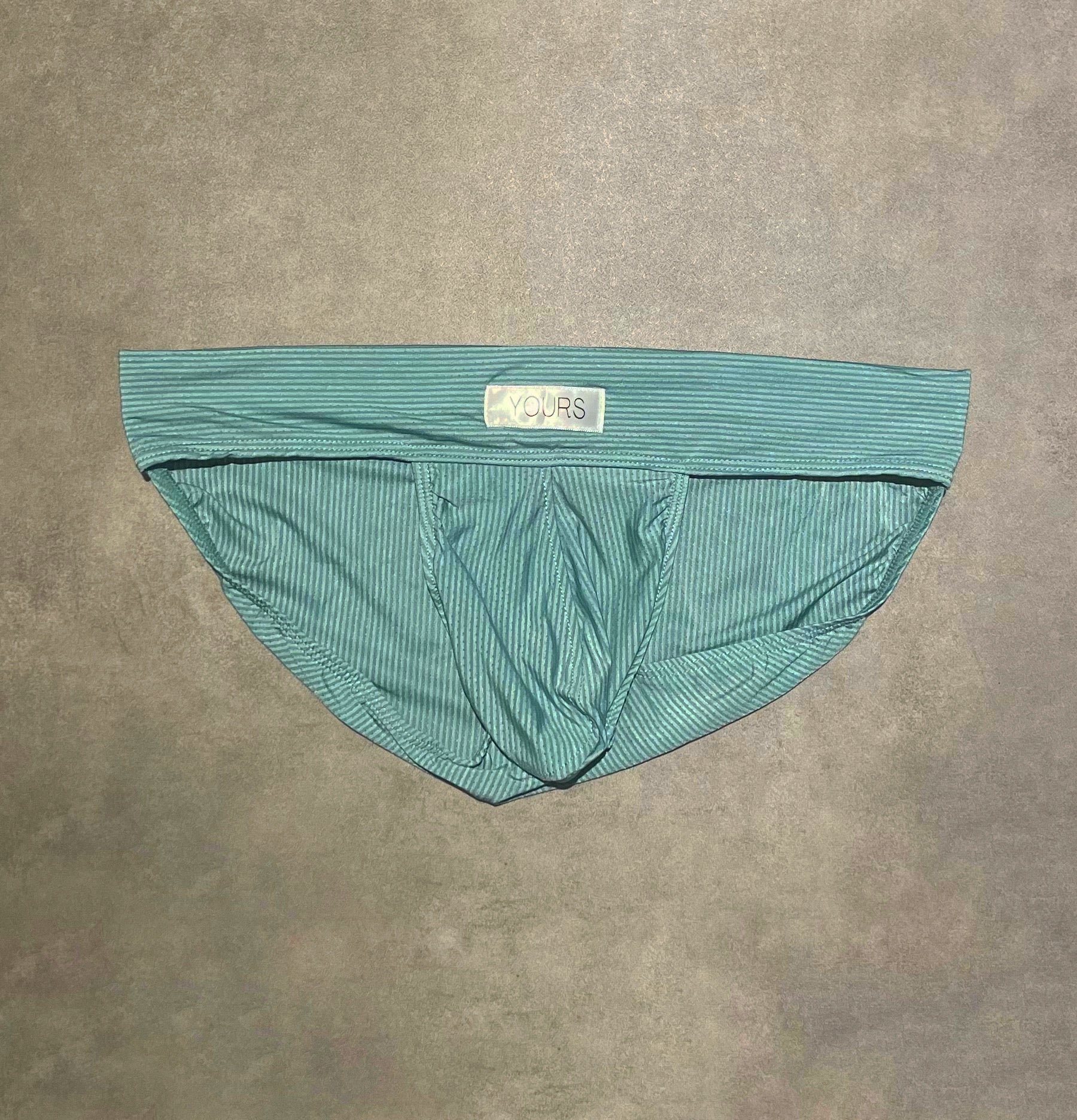 Flat lay photo of turquoise colored striped briefs